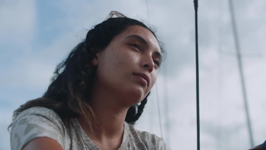 A woman tilts her head while sitting on a boat