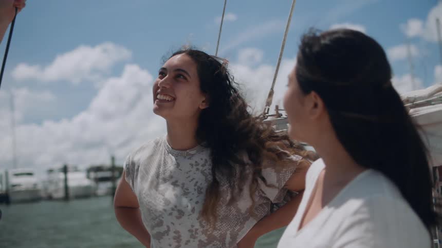 Two women standing on a boat and engaging in a lively conversation with someone who is also on the boat with them