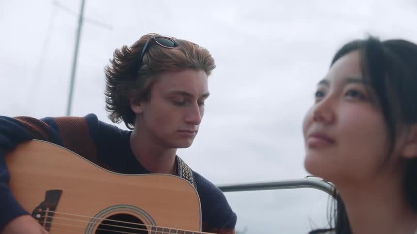 A woman listens to a man play guitar