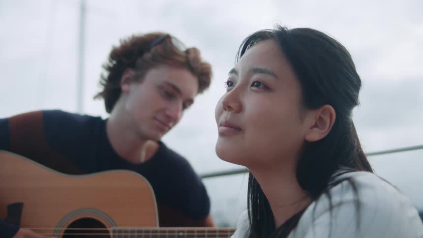 A woman listens to a man play guitar