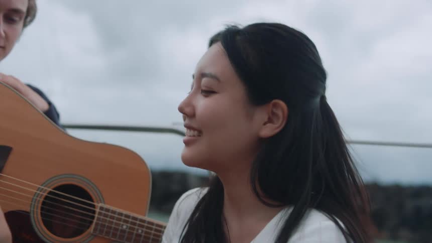 A woman smiling while talking to a man with a guitar outside