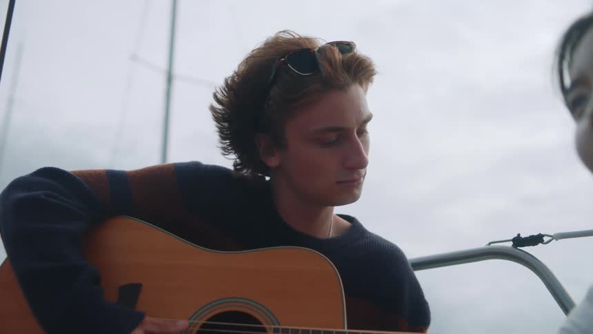 A woman is listening to a man play guitar
