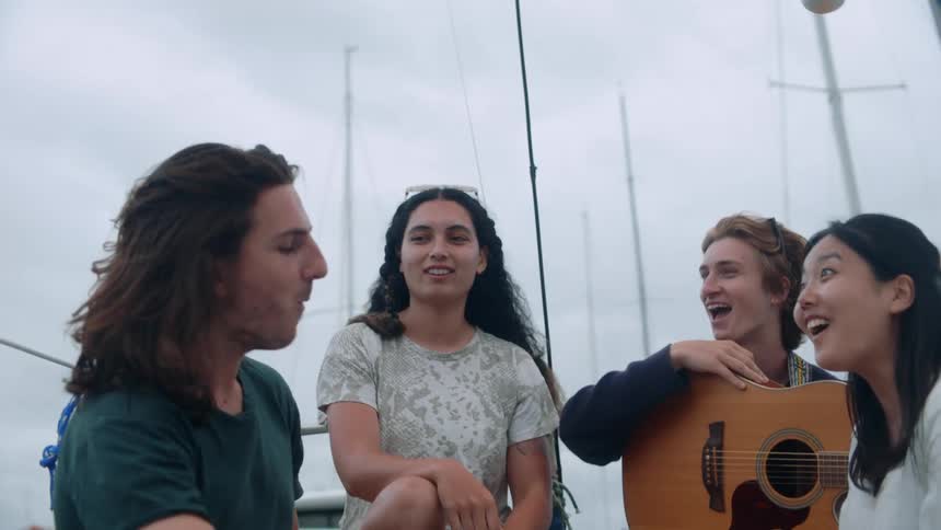 Group of young happy friends eat and talk together on a sailboat