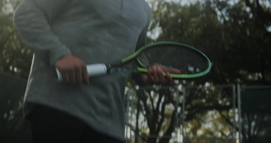 A man is jumping around playing tennis with a racket in his hand swinging at the ball