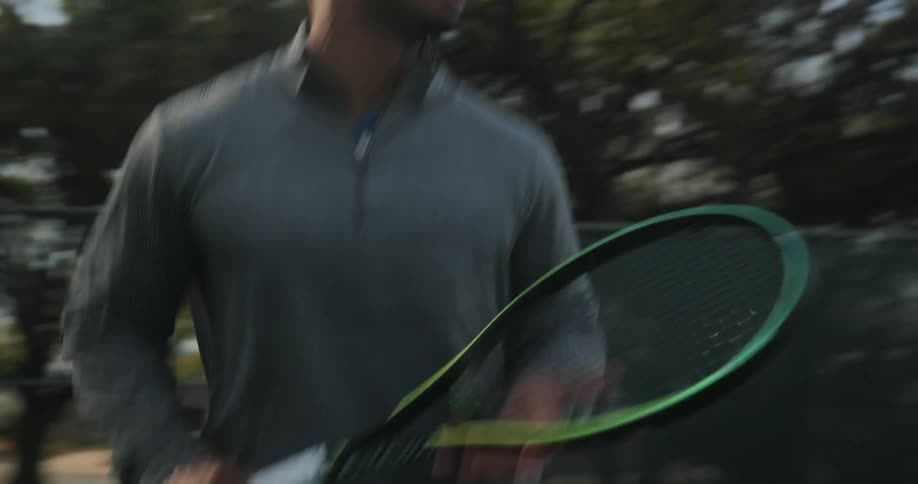 A man is playing tennis outdoors during the spring time