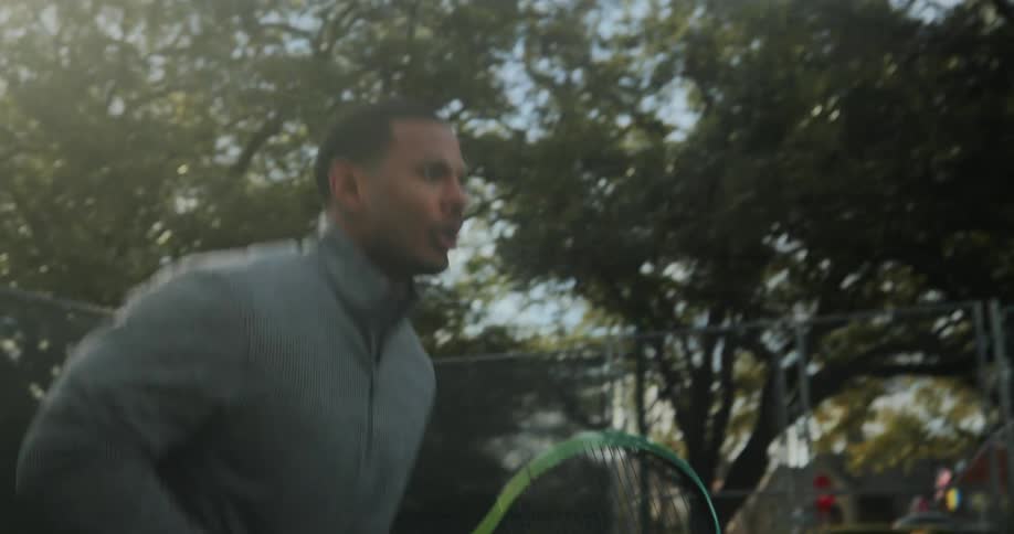 Determined man with gray shirt plays tennis in the court
