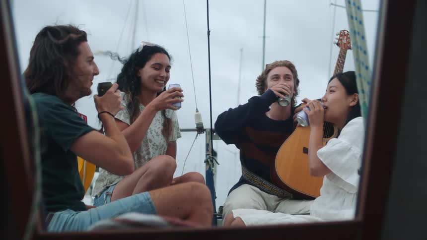 Friends hanging out on a sailboat drinking beer