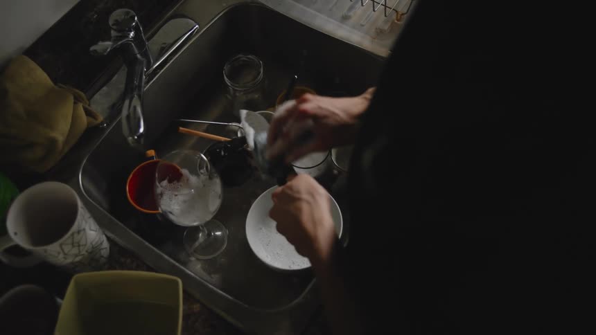 Woman with black shirt does the dishes in the kitchen