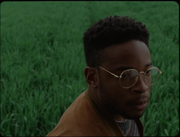 Man in a green grass angrily wearing his glasses in a sad face