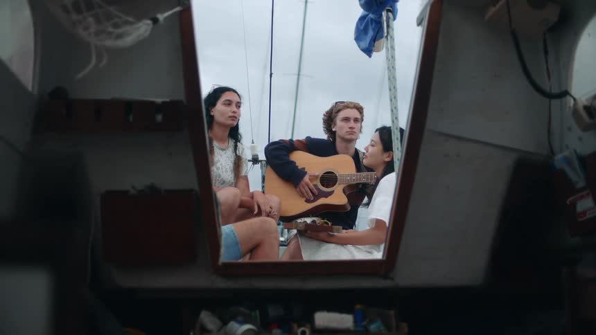 Friends listen to a man play guitar