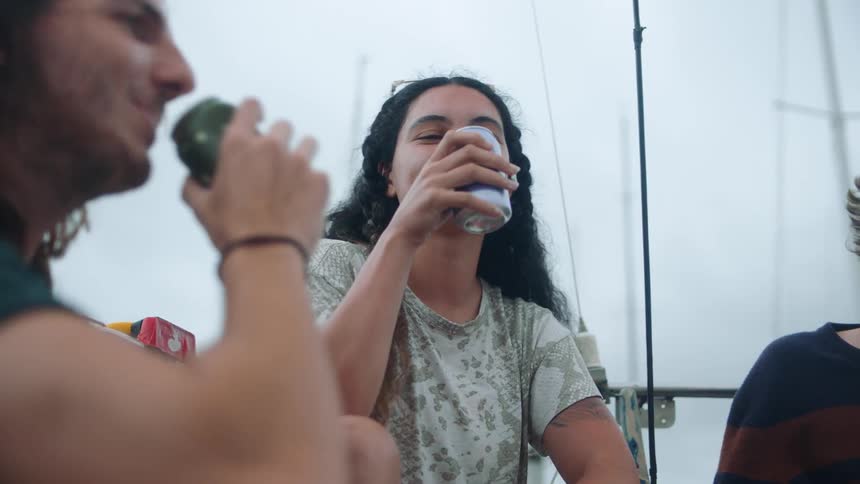 Friends hanging out on sailboat drinking beer toasting and laughing