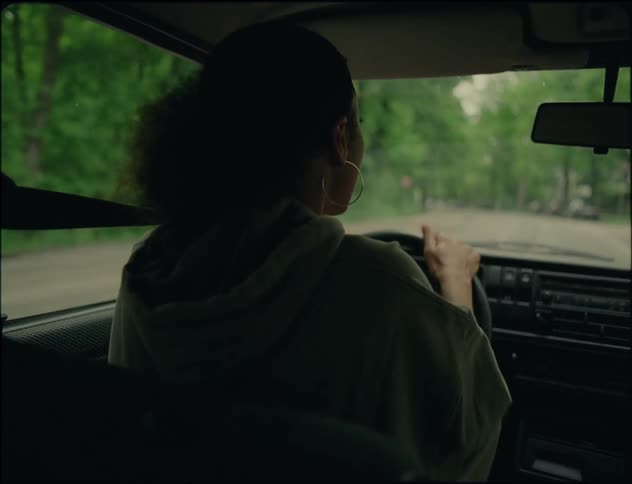 Woman with curly hair hoop earrings and gray hoodie argue with man while driving car on road