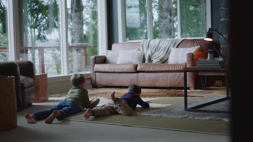 Two children color in the living room