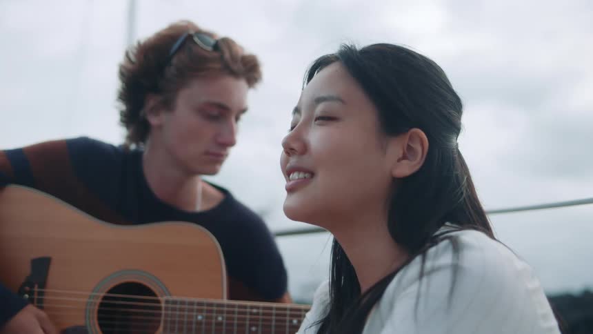 Male and female are sitting together and playing guitar
