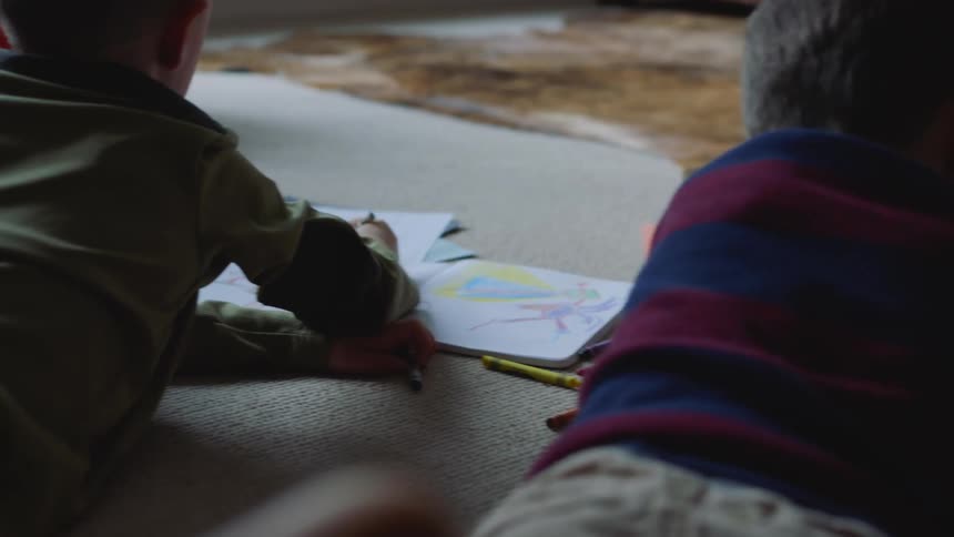 Two children color on the carpet