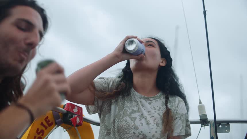 Man and woman have a drink while on their boat and happily taking the drink