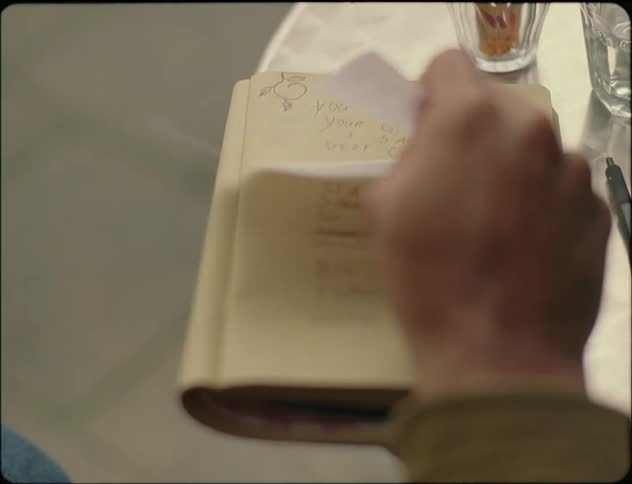 A person picking up a receipt placed on an open notebook