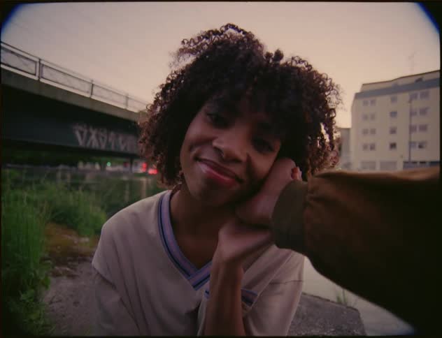A woman with a gentle smile on her face while someone touches her face in a romantic way