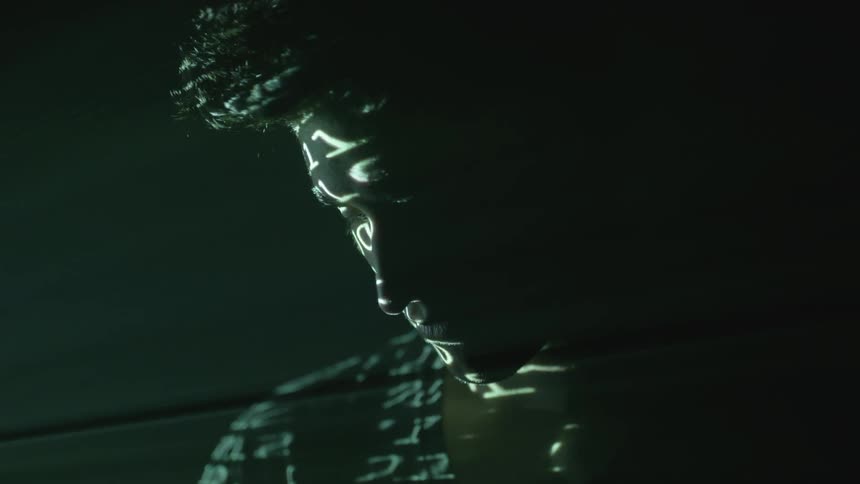 A man's face with shadows of numbers on his head