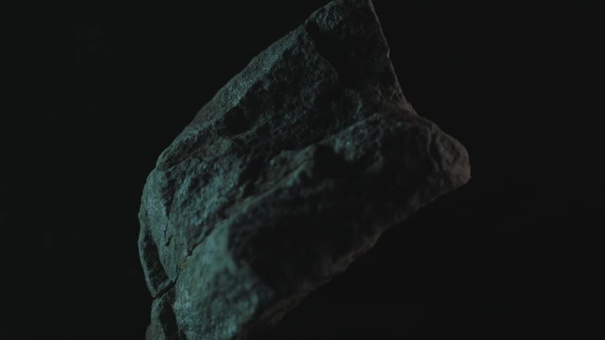 A porous rock revolves in the dark