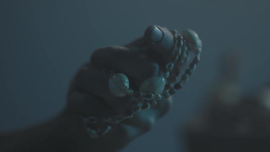 A person holds a beaded necklace in their hand