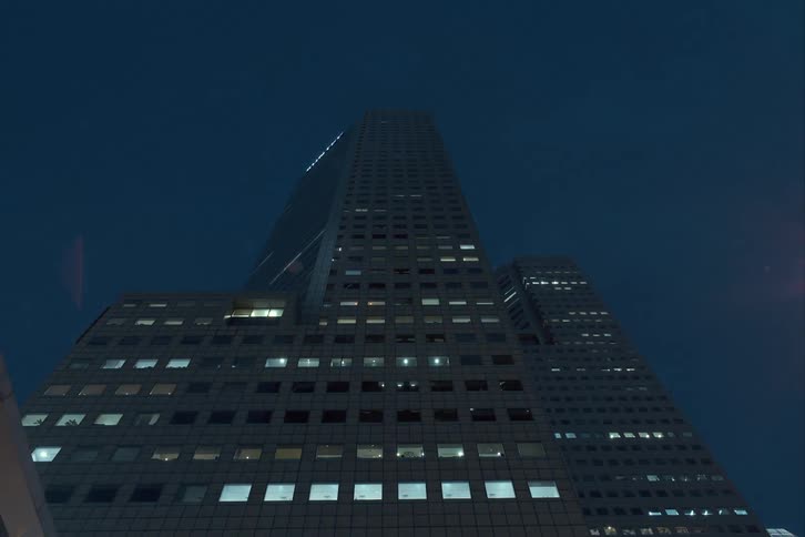 Building lights turn on as night falls over skyscraper