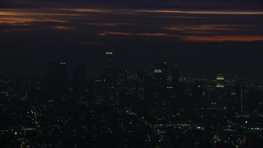 Aerial view of tall skyscrapers in Downtown Los Angeles at sunrise with a cloudy sky and winter morning backdrop