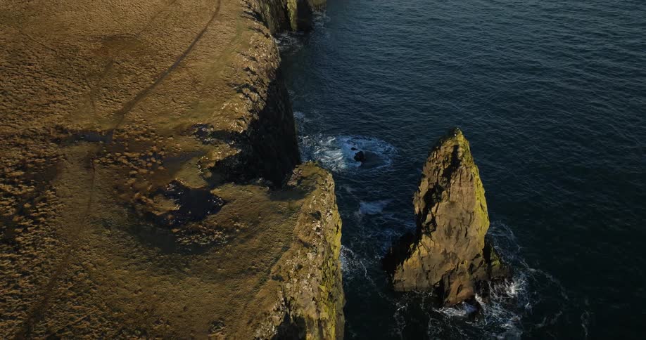 A large rock or cliff is shown with the ocean next to it