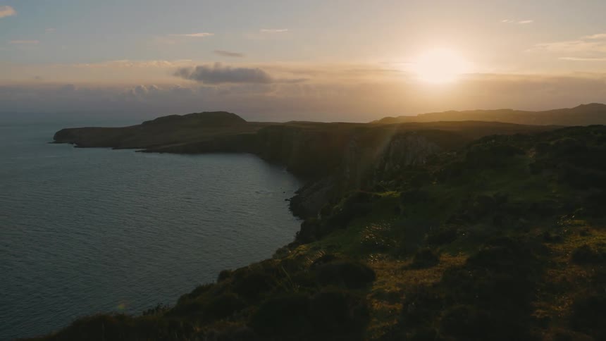Aerial view of the coastline a cape and an ocean bay at sunset
