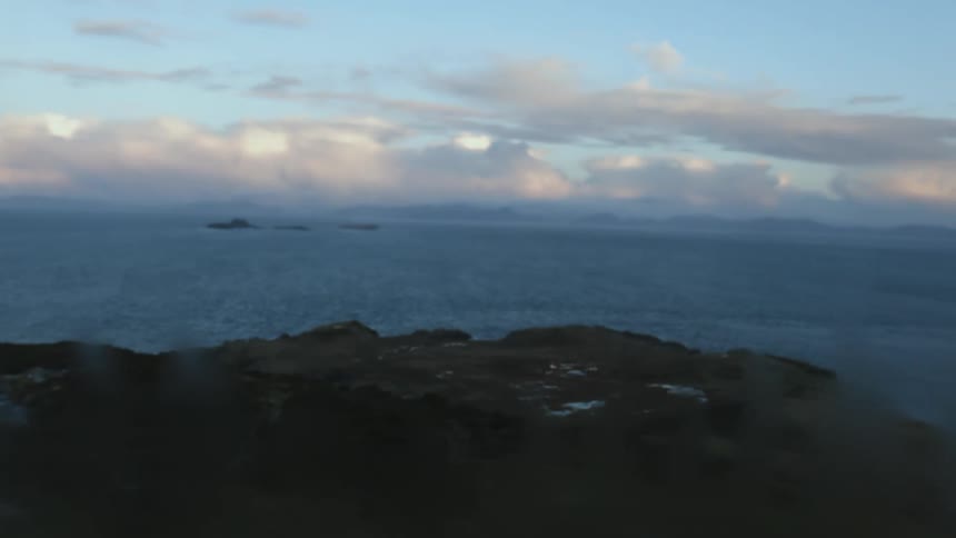 Landscape view of isles in the ocean comes to focus through a fogged window at evening