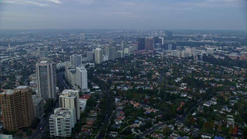 An aerial view of Wilshire Blvd over the Los Angeles Country Club and The Windmill Links during sunrise with a panoramic view of Century City and Beverly Hills California