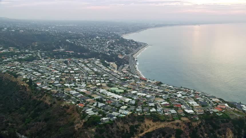Aerial footage of homes overlooking the ocean in Pacific Palisades California during the morning