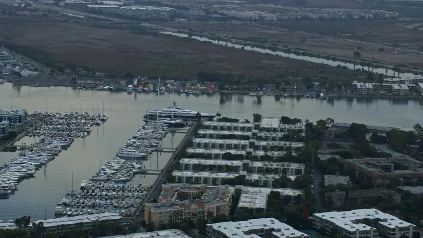 A mega yacht is seen docked at sunrise in Marina Del Rey while surrounded by waterfront apartment buildings and other boats in the harbor