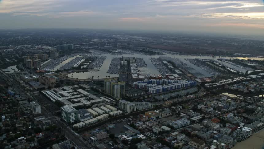 An epic sunrise aerial view from a Shotover F1 camera flying over Venice neighborhoods approaching and flyby Marina Del Rey harbor located on the coast of Southern California