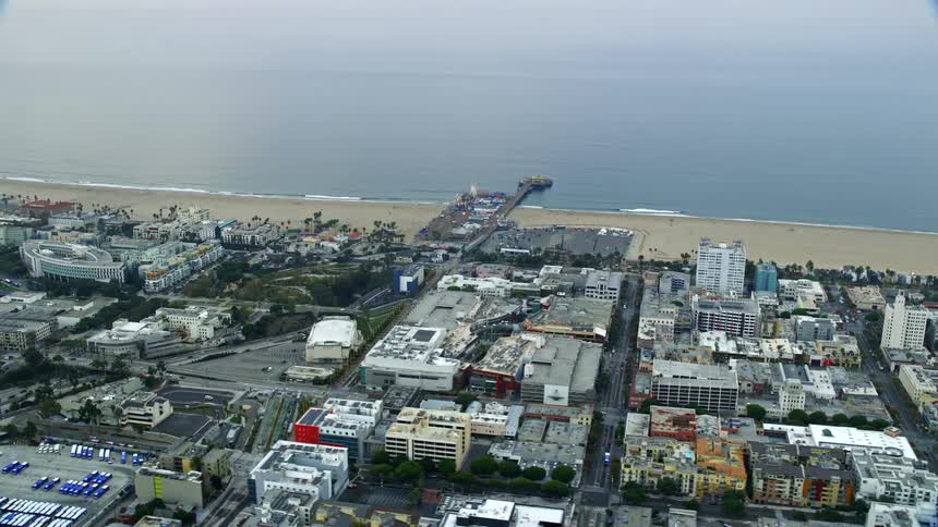 Aerial footage of beachfront shops near the iconic Santa Monica Pier during morning hours in Southern California