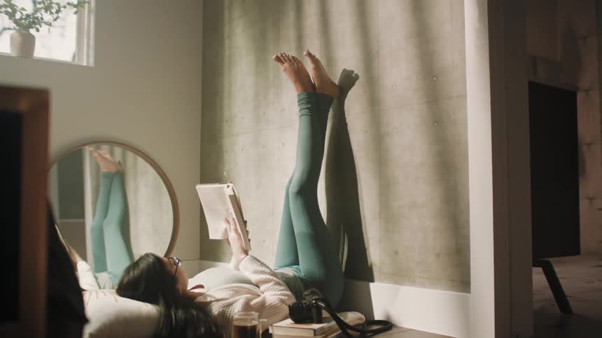 A woman is laying on the floor reading a book