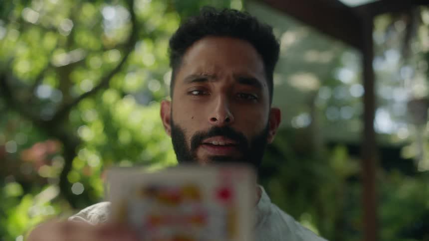 Man with beard demonstrating a card magic trick outdoors