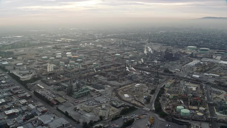 Aerial footage of an oil refinery in El Segundo California at sunrise showcasing the industrial and hazy atmosphere of the area
