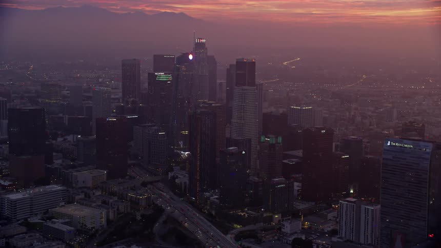 Aerial footage of downtown Los Angeles California at sunrise showcasing high-rise buildings hotels and skyscrapers with a winter haze in the air