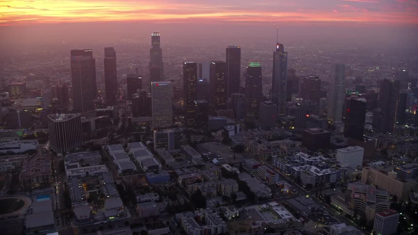 An Epic Helium shot features aerial footage of Downtown Los Angeles during a hazy sunrise showing high rise skyscrapers and superstructures