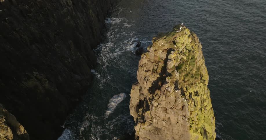 Aerial view of a tall promontory near a cliff on he coast at morning