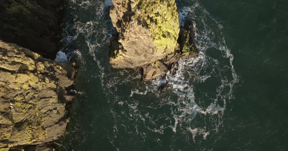 Waves splash against tall rock formations in the water