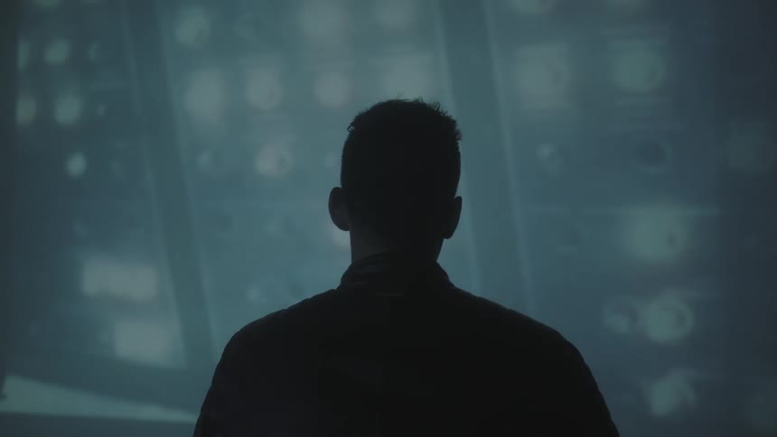 A man looks at lights flashing on a wall