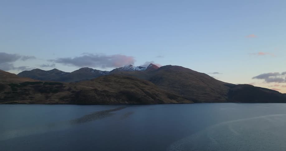 Aerial view of a mountain range on the coast next to the ocean at morning