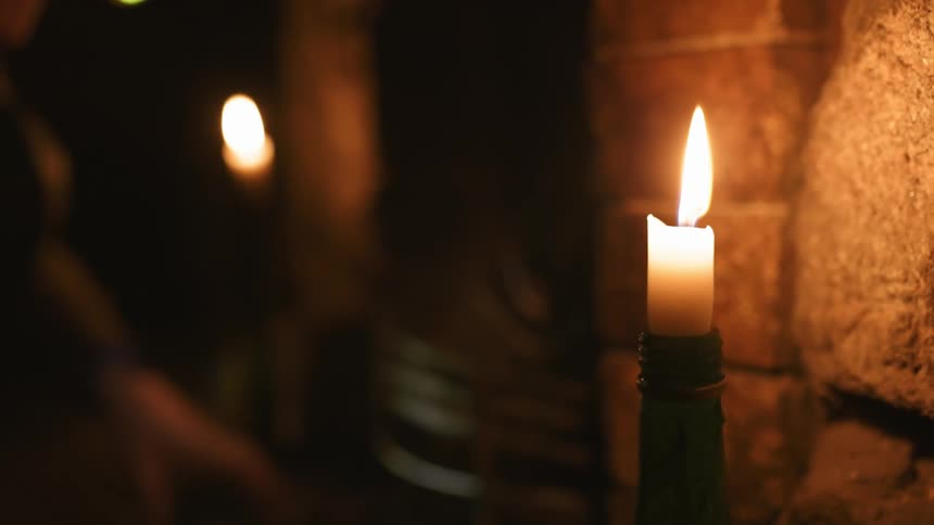 A person lighting candles and a fire in a fireplace