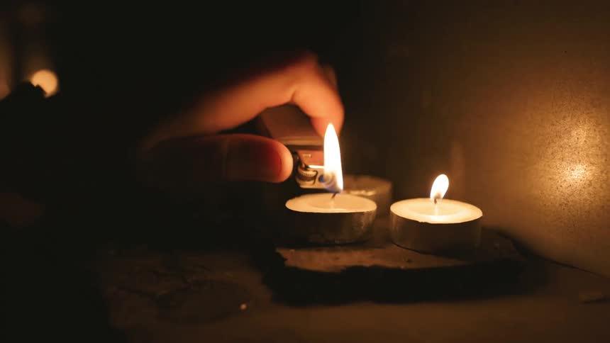 Lighting tea light candles with lighter in dark room