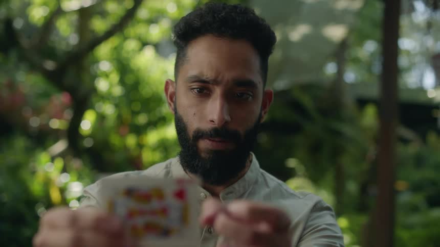 Man smiles while changing a king of hearts into an ace of spades during a magical card trick