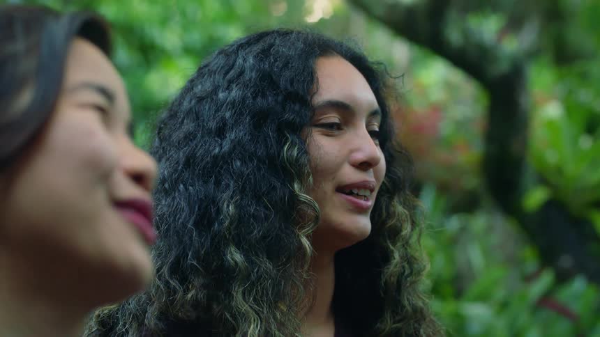 Two girls are focused on someone in front of them they are talking and laughing with
