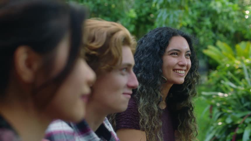 Three friends laugh while sitting in the park