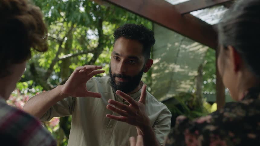 Magician perform card tricks in front of a happy couple in the garden
